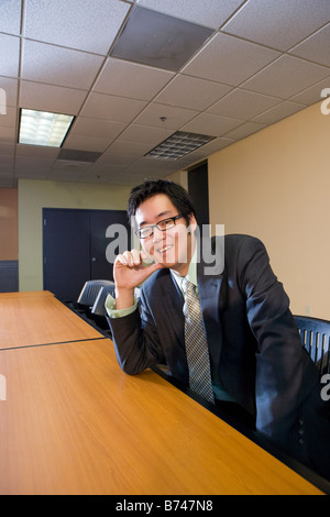 Junge asiatische Geschäftsmann stützte sich auf Konferenztisch im Sitzungsraum Stockfoto