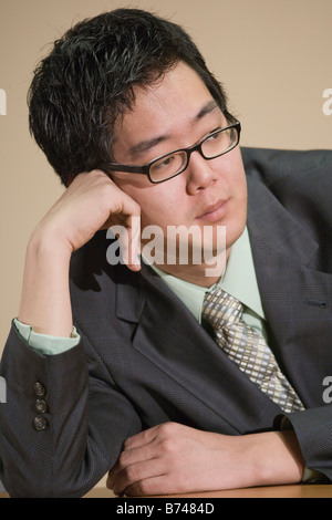 Nahaufnahme von jungen asiatischen Geschäftsmann stützte sich auf Ellbogen Stockfoto