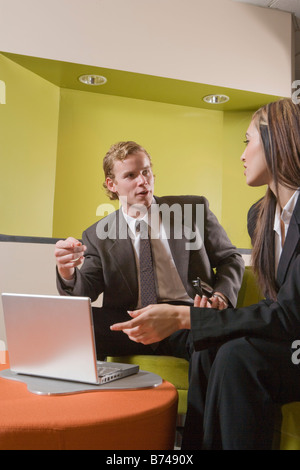 Zwei junge Büroangestellte im Gespräch und mit Blick auf laptop Stockfoto