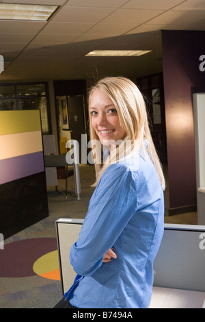 Junge weibliche Büroangestellte stützte sich auf Kabine Stockfoto