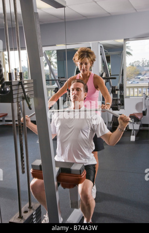 Paar mittleren Alters in Trainingskleidung mit Gerät für Krafttraining im Fitnessstudio Stockfoto