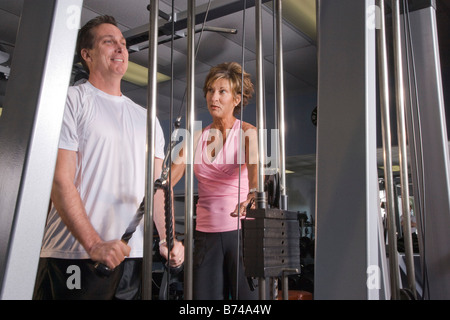 Paar mittleren Alters im Umgang mit Gerät für Krafttraining im Fitnessstudio Stockfoto