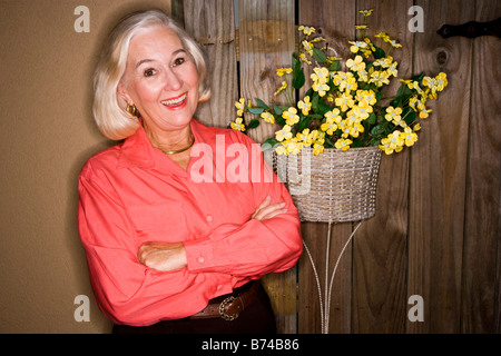Reife Frau, die durch die Holztür mit Blumen im Korb Stockfoto