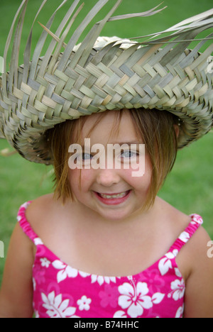 Ein Lächeln auf den Lippen 5 Jahres altes Mädchen trägt einen Strohhut und tropische Kleid schaut in die Kamera. Stockfoto