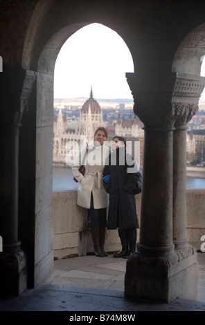 ZWEI UNGARISCHE MÄDCHEN AM FISHERMANS BASTION MIT DEM PARLIAMENT HOUSE IN DER FERNE AM PESTER UFER DER DONAU IN Stockfoto