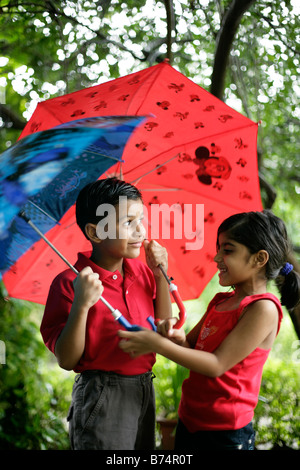 Schelmische Kinder in den Regen leichte Bewegung verwischen versucht die buntesten Regenschirm zu erhalten Stockfoto