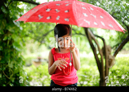 Unschuldiges junge Mädchen verloren in Gedanken halten Sie einen Regenschirm im Regen Stockfoto