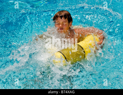 Grimassieren einen 10 Jahre alten junge Spritzer in ein Schwimmbecken Laguna Niguel CA Hinweis gelbe Float MODEL-RELEASE Stockfoto