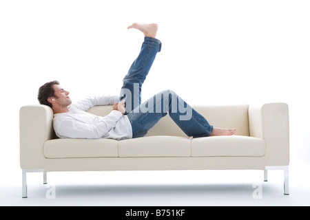 Eine Mitte erwachsenen Mann liegt auf Sofa hören mp3-player Stockfoto