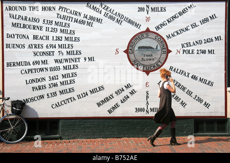 Frau, die Entfernung von Welt Ortsschild vorbei, während auf dem Handy in Nantucket Cape Cod USA sprechen Stockfoto