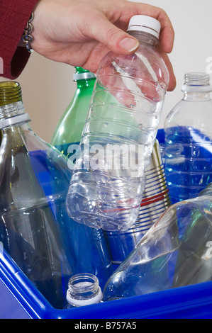 Hausfrau, die blaue Kiste voller Flaschen und Dosen für das recycling hinzufügen Stockfoto