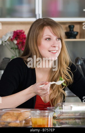 Frau Essen nehmen Sie Lebensmittel aus Containern und Gabel aus Mais hergestellt, und die sind vollständig kompostierbar, Winnipeg, Kanada Stockfoto