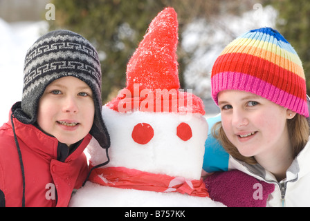 Junge Mädchen und jungen neben Schneemann, Winnipeg, Kanada Stockfoto