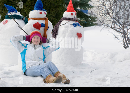 Dreizehn Jahre altes Mädchen entspannend neben Schneemänner, Winnipeg, Kanada Stockfoto