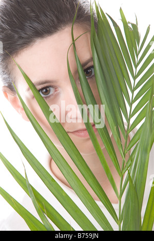 Gesicht einer jungen Frau, die hinter einem Blatt, Winnipeg, Manitoba Stockfoto