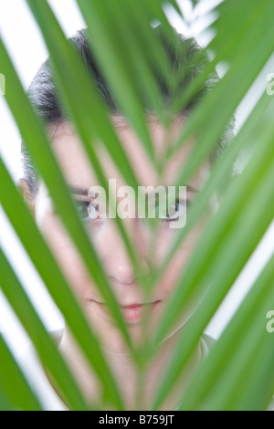 Gesicht einer jungen Frau hinter einem Blatt, Winnipeg, Manitoba Stockfoto