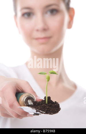 Gesicht einer jungen Frau mit einer Kelle und kleine Pflanze, Winnipeg, Manitoba Stockfoto