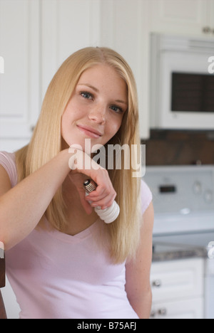 Junge Frau Betrieb kompakte Leuchtstofflampe in Küche, Brandon, Manitoba, Kanada Stockfoto