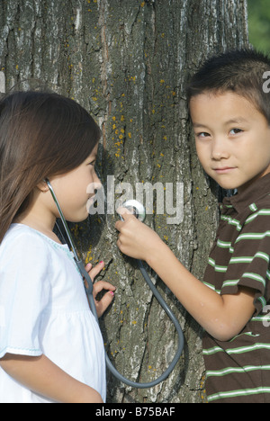 Fünf Jahre alte Schwester und sieben Jahre alten Bruder mit Stethescope am Baum, Winnipeg, Kanada Stockfoto