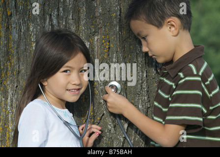 Fünf Jahre alte Schwester und sieben Jahre alten Bruder mit Stethescope am Baum, Winnipeg, Kanada Stockfoto