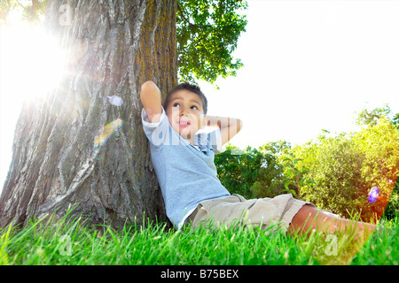 Sechs Jahre alter Junge sitzt neben Großbaum, Winnipeg, Manitoba, Kanada Stockfoto