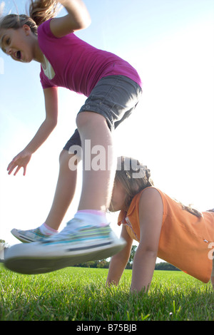 Sechs bis acht Jahre alten Schwestern spielen leapfrog, Winnipeg, Kanada Stockfoto