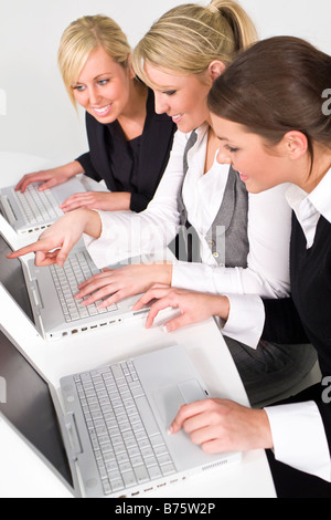 Ein Team von drei jungen Unternehmerinnen arbeiten auf ihren Laptops den Fokus auf diesem Bild ist die Frau in der Mitte Stockfoto