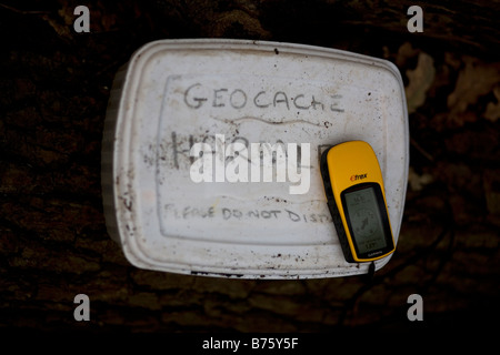 Geocache-Schatzkiste gefunden in der Landschaft mit einem GPS-Gerät an der Spitze Stockfoto