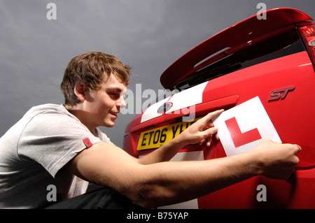 lächelnd Student Fahrer, setzt L Platten auf rotes Auto Stockfoto
