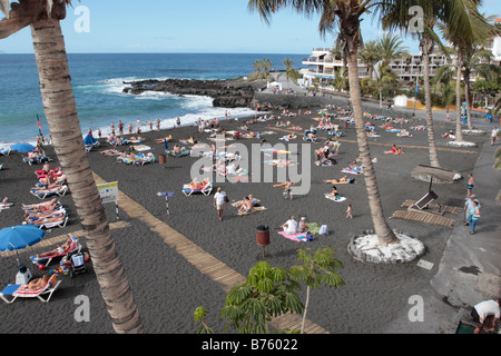 Touristen, die ein Sonnenbad im Dezember auf den Strand Playa Arena Teneriffa Kanaren Spanien Stockfoto