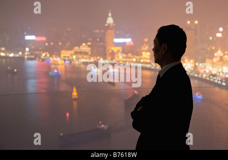 Die Silhouette eines Mannes, der Blick auf die beleuchtete Skyline von Pudong von einem hohen Aussichtspunkt. Stockfoto