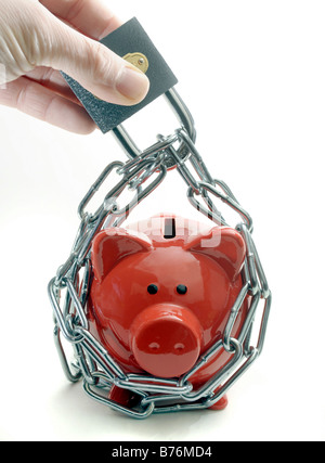 EIN ROTES SPARSCHWEIN GESCHÜTZT DURCH VORHÄNGESCHLOSS UND KETTE HELD IN MANS HAND. Stockfoto