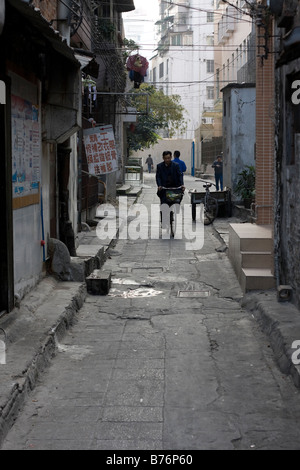 Mann Reiten Fahrrad allein an den ersten kalten Morgen im Jahr morgens eine Seitenstraße Gasse in Guangzhou China Black und Stockfoto