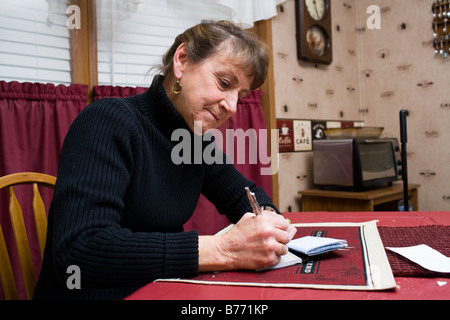 Eine Frau, die einen Scheck, monatlichen Rechnungen zu bezahlen. Stockfoto