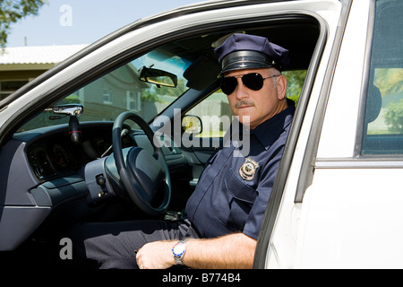 Schöne Reife Polizisten im Dienst sitzt in seinem Streifenwagen Stockfoto