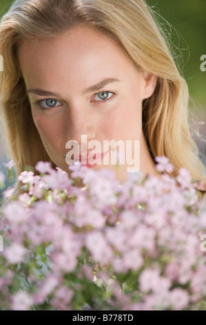 Frau posiert hinter Blumen Stockfoto