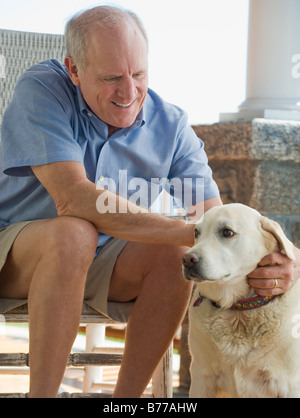 Ältere Mann sitzt auf der Veranda-Hund Stockfoto