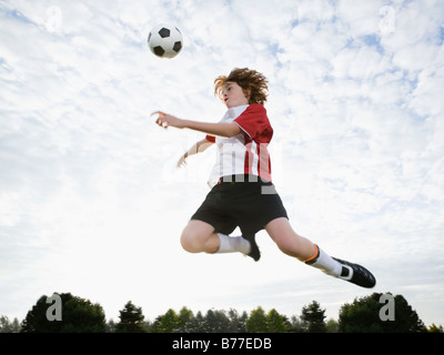 Junge springt in Richtung Fußball Ball mitten in der Luft Stockfoto