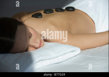 Frau Handauflegen Massage Tisch warmen Steinen auf Rückseite Stockfoto