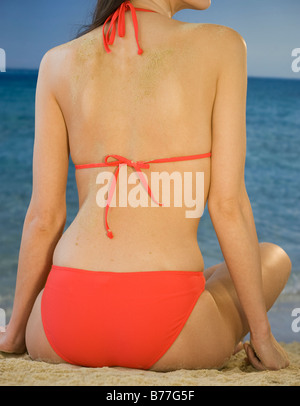 Rückansicht der Frau Bikini am Strand sitzen, Nahaufnahme Stockfoto