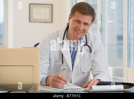 Männlichen Arzt posiert Schreibtisch Stockfoto