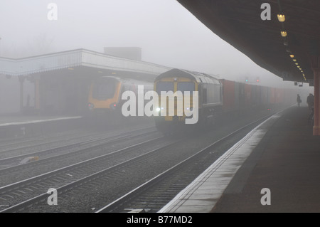 Güter- und Personenverkehr Züge im Winternebel am Bahnhof, UK Stockfoto