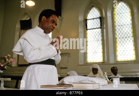 Brotherhood Of The Cross und Star, Moss Side Manchester, UK, 1993 A Priester faltet seine Hände im Gebet während einer Taufe. Stockfoto