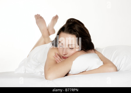 Junge Brünette Frau im Bett liegend, Augen geschlossen Stockfoto