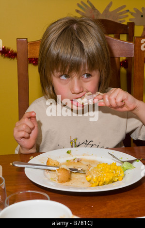 Junge mit gesundem Appetit, der eine gesunde ausgewogene Mahlzeit aus Hühnerkartoffel Mais und Brokkoli isst Stockfoto