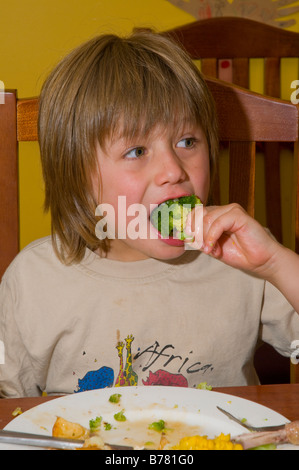 Junge mit gesundem Appetit, der eine gesunde ausgewogene Mahlzeit aus Hühnerkartoffel Mais und Brokkoli isst Stockfoto