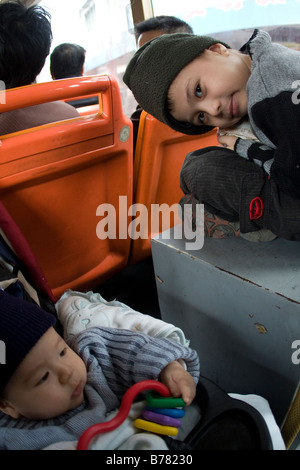 Zwei Brüder auf öffentlichen Stadtbus in Guanjgzhou China Wannenoberflaeche globalen Wirtschaftskrisen Violatign Chinas ein-Kind-Politik Stockfoto