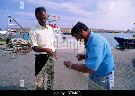 Italien, Kalabrien, Crotone, Hafen, Fischer, die die Netze reparieren Stockfoto