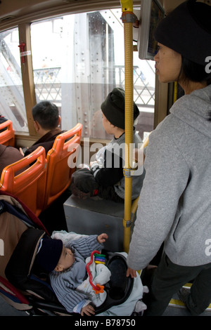 Junge Mutter mit zwei Kindern auf öffentlichen Stadtbus in Guanjgzhou China Verkalkung globalen Wirtschaftskrisen Stockfoto