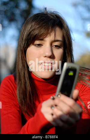 Herr Porträt eines niedlich und süß spanische Teenager-Mädchen eine Botschaft mit ihrem Telefon im park Stockfoto